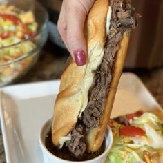 a hand holding a sandwich over a bowl of food