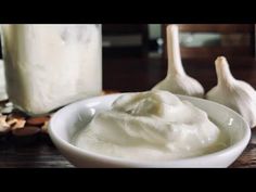 a white bowl filled with cream next to garlic