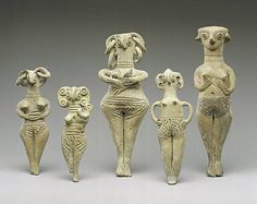 five ancient ceramic figurines are standing in a row on a gray background,