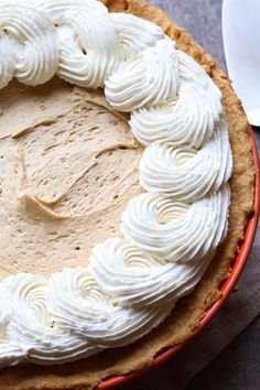 a pie with white frosting on top sitting on a table next to a fork