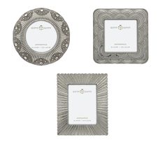 three silver frames sitting next to each other on top of a white surface with an ornate design in the middle