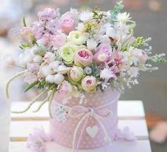 a pink vase filled with lots of flowers on top of a table