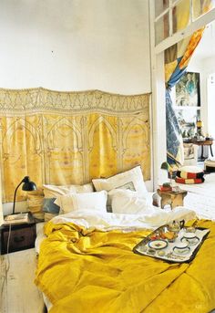 a bed with yellow comforter and pillows in a room that looks like it has been decorated