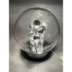 a clear glass ball with some black balls in the center on a silver table top