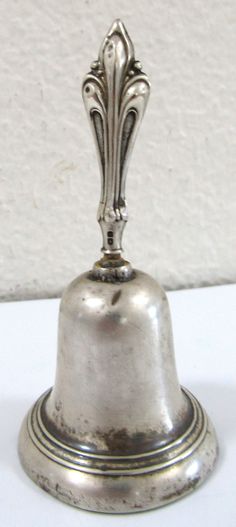 an antique silver bell on a white surface