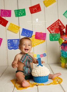 a baby sitting in front of a birthday cake