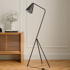 a black floor lamp sitting on top of a hard wood floor next to a white wall