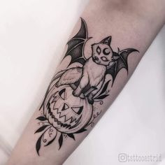 a bat and pumpkin tattoo on the arm