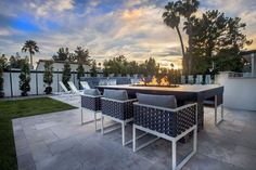 an outdoor dining area with fire pit and lounge chairs at the end of the patio