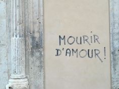 the word mourir d'amour is written in black ink on a wall