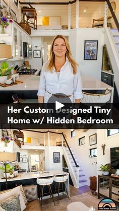 a woman standing in front of a living room and kitchen with stairs leading up to the second floor