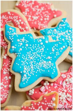 decorated cookies with blue, red and white icing on a wooden table in the shape of stars