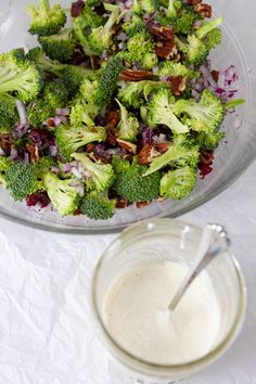 a bowl filled with broccoli and onions next to a container of ranch dressing