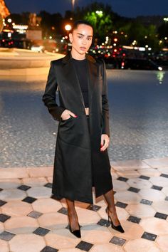 a woman standing in front of a fountain at night