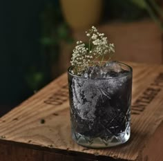 a glass filled with ice and flowers on top of a wooden table