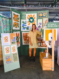 a woman is standing in front of some art work on display at an exhibit booth