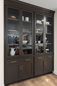 a kitchen with wooden floors and glass doors on the front cabinets, along with a white pitcher