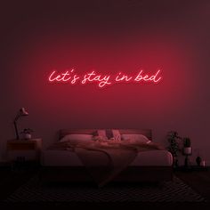 there is a neon sign that says let's stay in bed on the wall