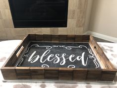 a wooden tray with chalk writing on it that says, beseld in front of a fireplace