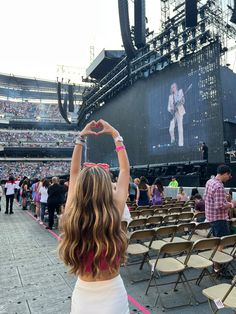 a woman is holding up her cell phone in front of an audience at a concert