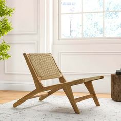 a wooden chair sitting on top of a white rug next to a potted plant