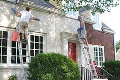 two men are painting the outside of a house