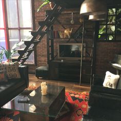 a living room filled with furniture and a fire place in front of a brick wall