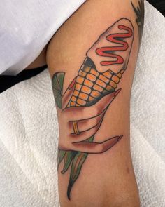 a tattoo on the leg of a person holding a corn cob