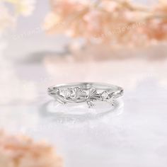 a close up view of a wedding ring with flowers in the background