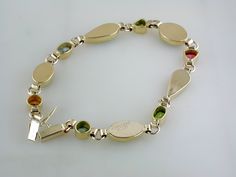 Ethiopian opals, topaz, tanzanite, citrine, peridot, tourmaline, green diopsite of various shapes and sizes are each delicately set in handmade bezels. This 14k yellow gold bracelet has been hand signed by the artist. 14K Yellow Gold & 22K Yellow Gold Ethiopian opals, topaz, tanzanite, citrine, peridot, tourmaline, green diopsite 7 1/4" long Plunger Clasp with figure 8 safety 9mm at widest point Weighs approximately 8.4 grams Hand Signed Available for Order. (Orders Placed today will ship in Yellow Gold Multi-stone Oval Bracelets, Yellow Gold Multi-stone Oval Bracelet, Elegant Multi-stone Peridot Gemstones, Heirloom Gold Multi-stone Bracelets, Yellow Gold Oval Bracelet With Multi-stone, Yellow Gold Oval Multi-stone Bracelet, Heirloom Gold Bracelets With Multi-stone, Heirloom Yellow Gold Multi-stone Bracelets, Gold Oval Fusion Gemstones