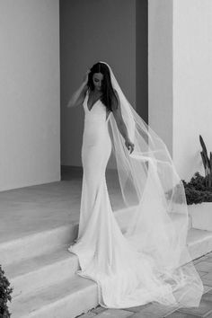 a woman in a wedding dress is standing on the steps with her veil over her head