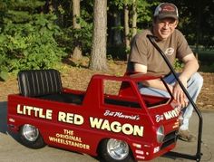 a man kneeling down next to a little red wagon