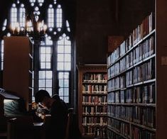 a person sitting at a table in front of a book shelf filled with books