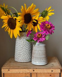 two white vases with yellow and purple flowers in them