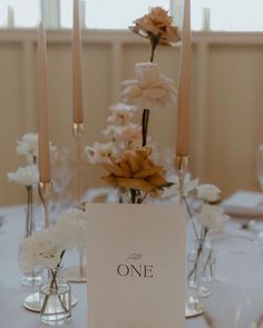 the table is set with candles, flowers and a sign that says one on it