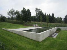 an image of a concrete pool in the middle of a field with trees behind it