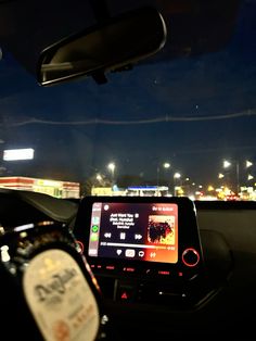 the dashboard of a car with an electronic device on it's display screen and lights in the background