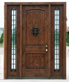 a person standing in front of a wooden door with glass inserts on the side