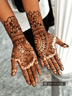 a woman's hand with henna tattoos on it and her hands in the shape of flowers