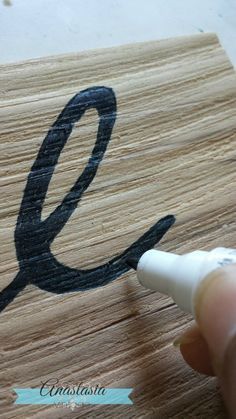 someone is drawing the letter e on a piece of wood