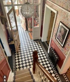 an aerial view of a hallway with stairs and chandelier hanging from the ceiling