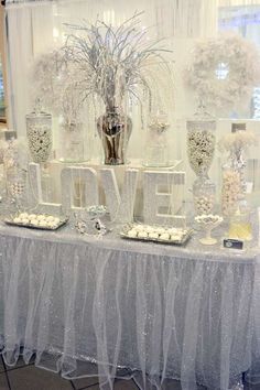 a table topped with lots of vases filled with white flowers and candy bar covered in frosting