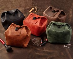 four different colored leather bags sitting on top of a table next to a brush and comb