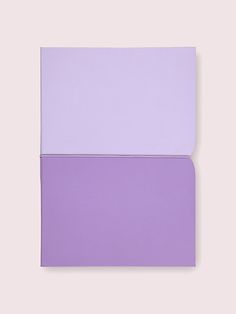 two different colors of paper on a pink and purple background, one is folded in half