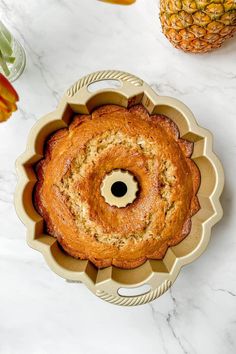 a pineapple bundt cake sitting on top of a table next to some fruit