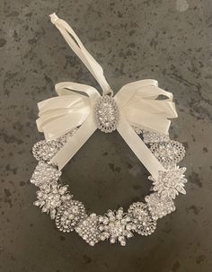 a white wreath with bows and jewels on it sitting on top of a granite counter