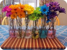 there are many different colored flowers in glass vases on the dining room table,