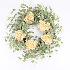 an overhead view of a wreath with yellow flowers and greenery on white background, top view