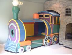 a toy train sitting on top of a white floor next to a brick wall and fireplace