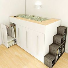 a room with a bed and some drawers on the floor next to a shelf filled with clothes